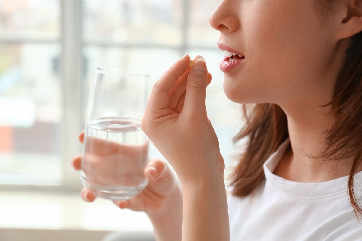 Woman drinking water with probiotic capsules