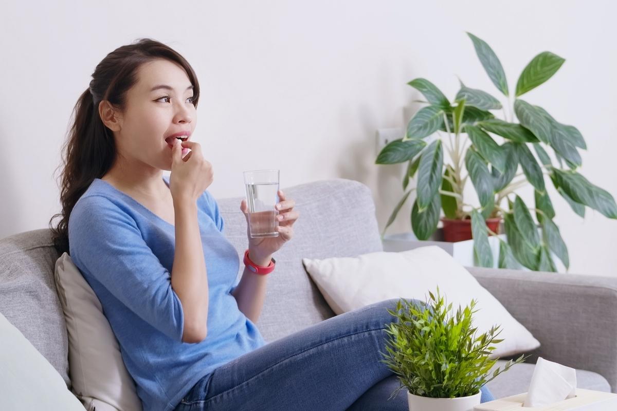 Woman taking daily probiotic supplement capsule