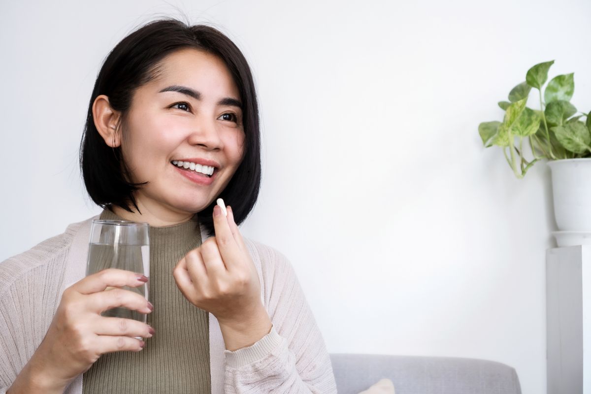 A woman taking a probiotic pill.